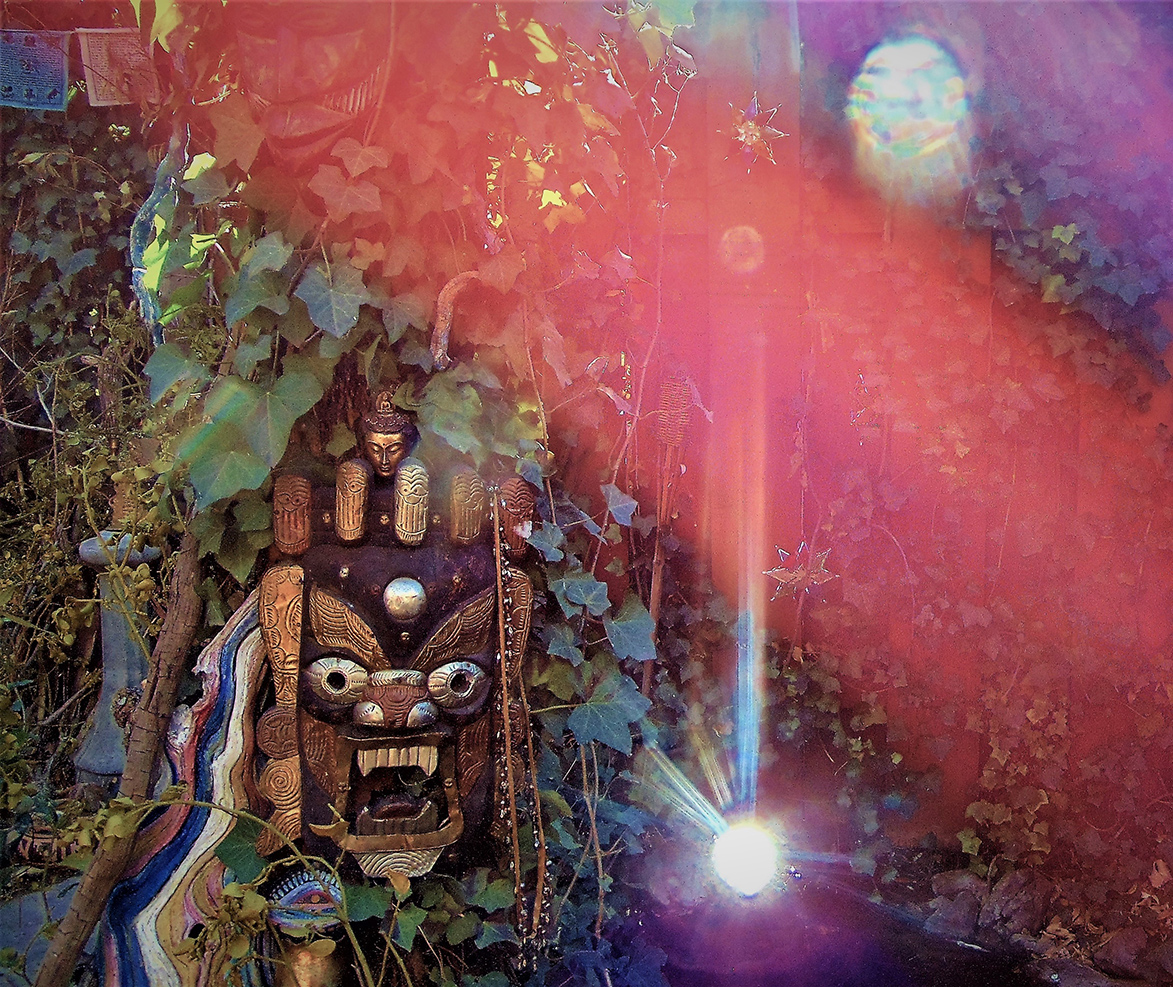 Garden Guardian by Usha Lamat, a photograph of a carved ceremonial figure surrounded by lush garden vines and dramatic radiant light flare