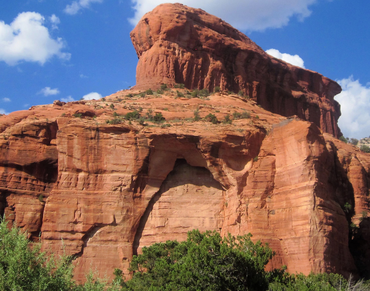 Hidden Entrance by Usha Lamat, a Sedona landscape photograph of a red rock cliff with a cave-like recessed opening beneath a blue sky